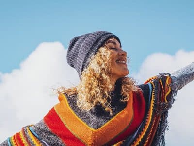 Joyful woman with arms outstretched against blue sky